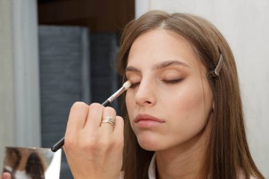 Makyaj yapma süreci. Makyaj sanatçısı bir bru ile çalışıyor