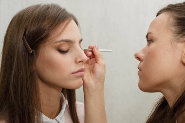 Makyaj yapma süreci. Makyaj sanatçısı bir bru ile çalışıyor