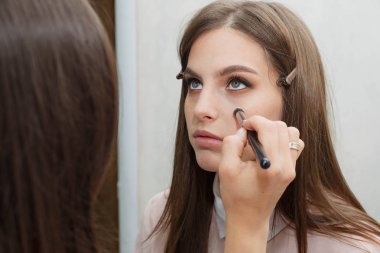 Makyaj yapma süreci. Makyaj sanatçısı bir bru ile çalışıyor