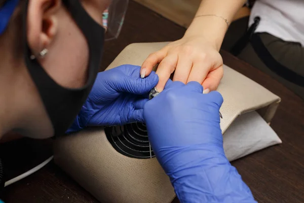The master of nail service removes the decoration from the clients nail with forceps