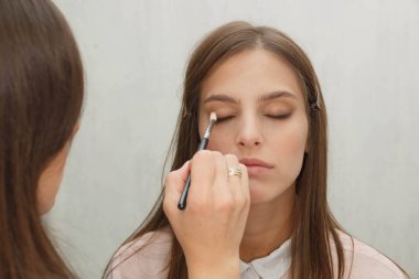 Makyaj yapma süreci. Modelin yüzünde bir fırça ile çalışan makyaj sanatçısı.