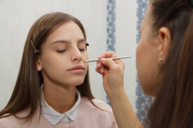Makyaj yapma süreci. Makyaj sanatçısı bir bru ile çalışıyor