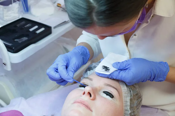 Woman on eyelash extension procedure, lamination of eyelashes in a beauty salon.