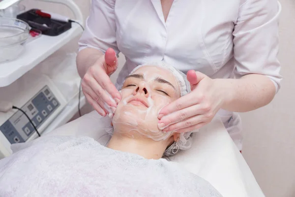 Aplicando espuma no rosto da menina antes do procedimento de mesoterapia — Fotografia de Stock