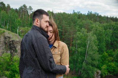 Bir adam bir dağın tepesinde bir kadına sarılır..