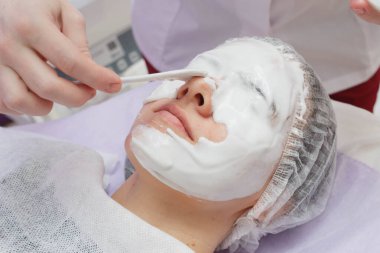 A cosmetologist does an ultrasonic cleaning of the skin of the face. clipart