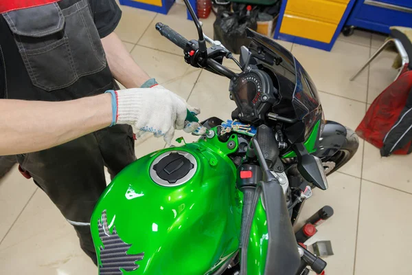 Repair and maintenance of motor vehicles. The master performs maintenance on the motorcycle. Service maintenance of a motorcycle.