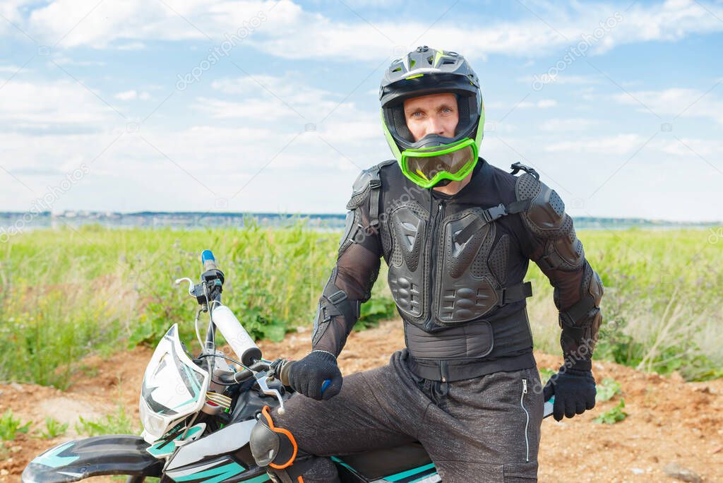 A man in motorcycle equipment sits on an enduro motorcycle. Motocross rider in action. Motocross sport. Extreme off-road race. Hard enduro motorbike.