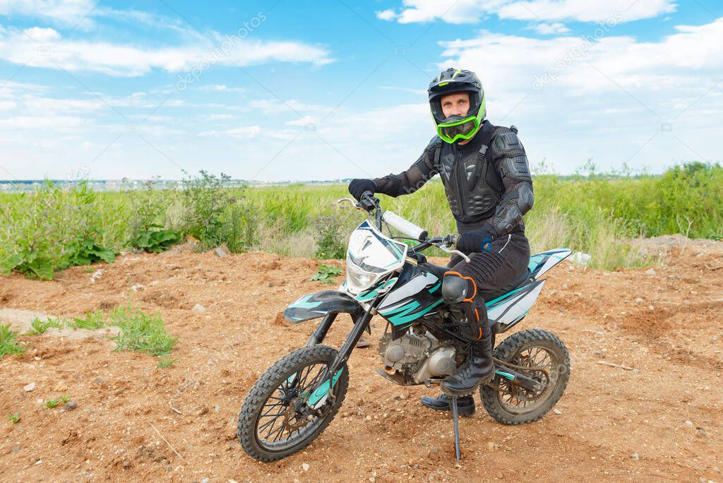 A man in motorcycle equipment sits on an enduro motorcycle. Motocross sport. Extreme off-road race. Hard enduro motorbike.