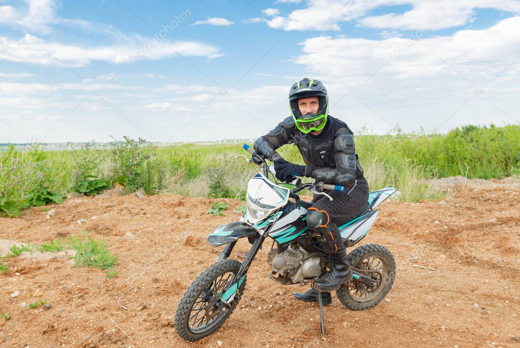 A man in motorcycle equipment sits on an enduro motorcycle. Motocross rider in action. Motocross sport. Extreme off-road race. Hard enduro motorbike.