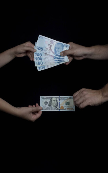 Руки взрослых людей, показывающих, сколько обменный курс между ста американским долларом и турецкой Лирой после всеобщих выборов в Турции. Крупным планом, на его черном фоне
.