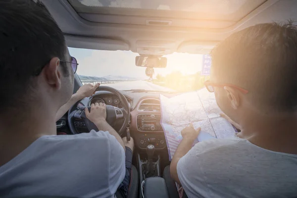 Two man having a trip by Fiat car and looking to the map for choosing the place to go.