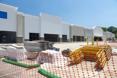 Bir perakende alışveriş merkezi İnşaat tarafından turuncu örgü çit. İnşaat malzemeleri Park yerinde yığınlanmış.