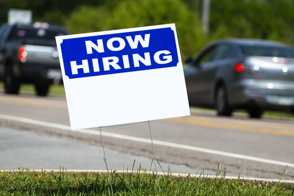 Yakın çekim yatay bir kadeh kopya alanı ile yol kenarında şimdi işe işareti. Flu arka plan olduğunu.