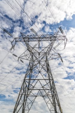 Bulutlu gökyüzü altında dikey atış yüksek gerilim elektrik hatları ve Kulesi. Yukarı doğru seyir.