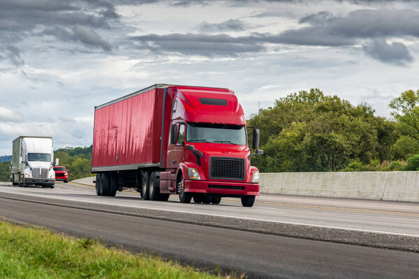 Horizontal shot of a red semi tractor-trailer truck traveling the interstate highway