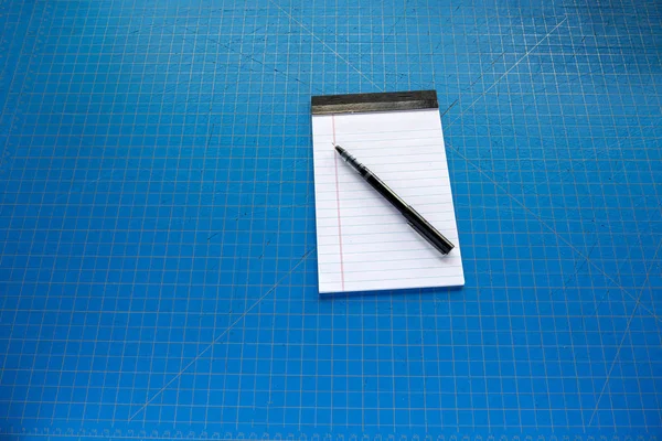 Mavi kesme tahtasına karşı kalemli boş beyaz yasal ped. — Stok fotoğraf