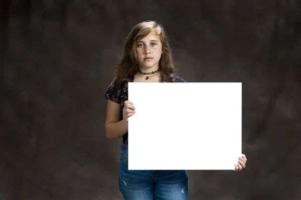 Serio guardando pre-giovanissima ragazza con lentiggini holding vuoto segno — Foto Stock