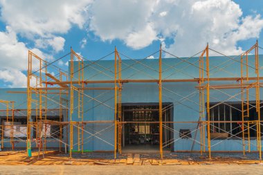 İnşaat halindeki yeni bir ticari binayı çevreleyen iskelenin yatay görüntüsü.