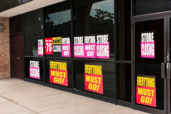 Horizontal angled shot of the windows of a store plastered with going out of business signs due to the pandemic.