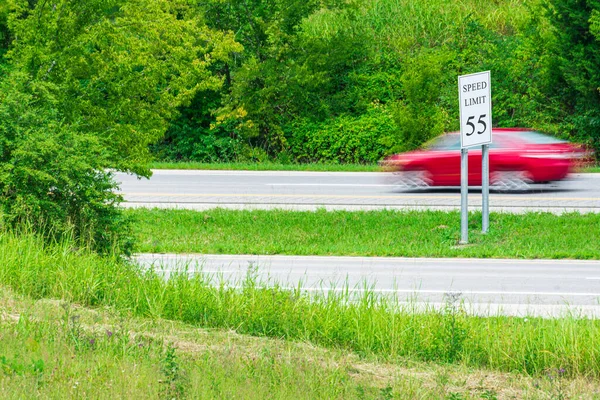 Горизонтальный Снимок Превышения Скорости Красной Машины Бегущей Знаку Ограничения Скорости — стоковое фото