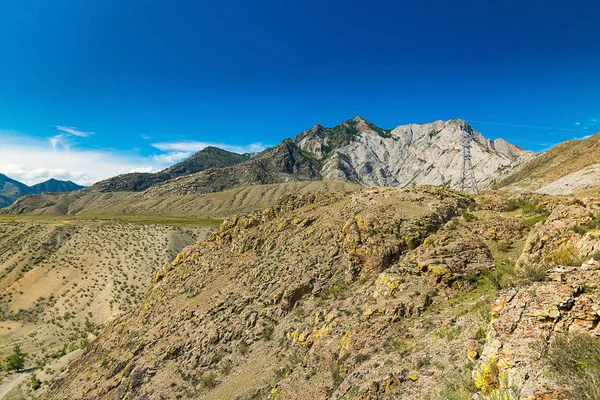 Rocky surface of wild mountains, Altai Republic, Russia. the surface of hills and mountains, dry rocky soil, mountains in the distance, power lines in the wild mountains