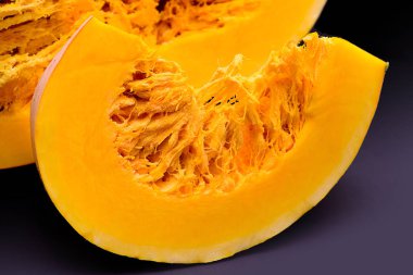 Kabak ile tohum ve lif kabak koyu arka plan üzerinde yakınındaki bir parça. Hangi portakal arka plan balkabağı tohumları ve lifleri ile bir parça