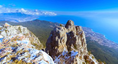 Ai-Petri Dağı, Mishor, Kırım, Ukrayna, kuş uçuşu yüksekliğindeki iki güverte manzarası. Önünde, çarmıhın tepesinde, solunda kar var. Dağların ardında birkaç şehrin manzarası var. Deniz ve bulutlu mavi bir gökyüzü.