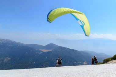 Türkiye, Ölüdeniz, Babadağ dağ, 30 Temmuz 2018, yamaç paraşütü uçuşları, sarı yamaçparaşütü dağlar ve gökyüzü önünde onun uçuş başlar.