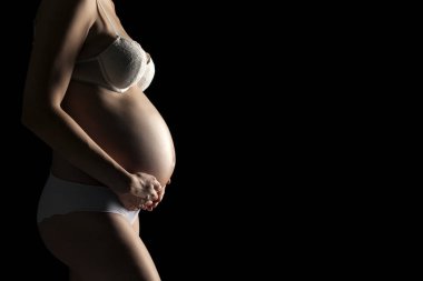 Siyah bir zemin üzerine beyaz iç çamaşırı Genç bir hamile kadın silüeti