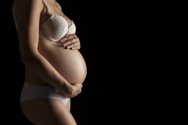 Siyah bir zemin üzerine beyaz iç çamaşırı Genç bir hamile kadın silüeti