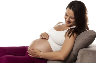 Mutlu güzel hamile kadın beyaz bir arka plan bir yatakta yatarken