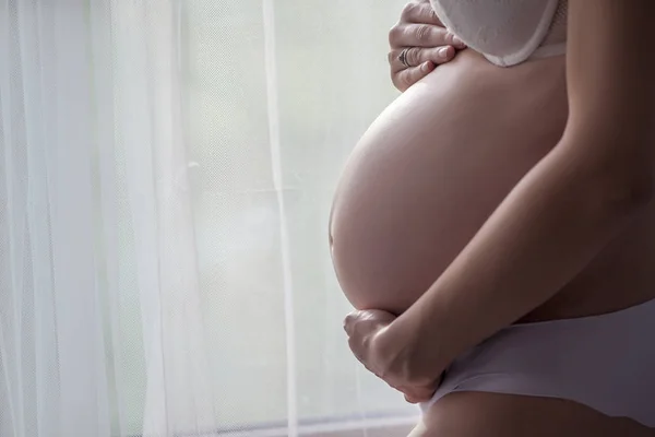 Brzuch Kobiety Ciąży Białej Bieliźnie Stojący Obok Okna Zasłony — Zdjęcie stockowe