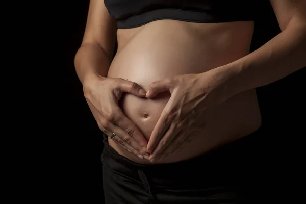 Brzuch Kobiety Ciąży Kształcie Serca Ręce Ciemnym Tle — Zdjęcie stockowe