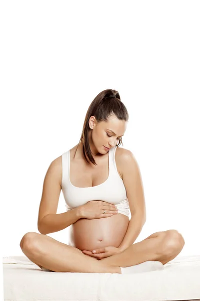 Mladá Těhotná Žena Sedící Posteli Lotosové Pozici Bílém Pozadí — Stock fotografie