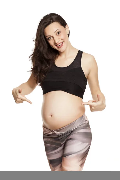 Hermosa Mujer Embarazada Sonriente Posando Sobre Fondo Blanco Apuntando Barriga —  Fotos de Stock
