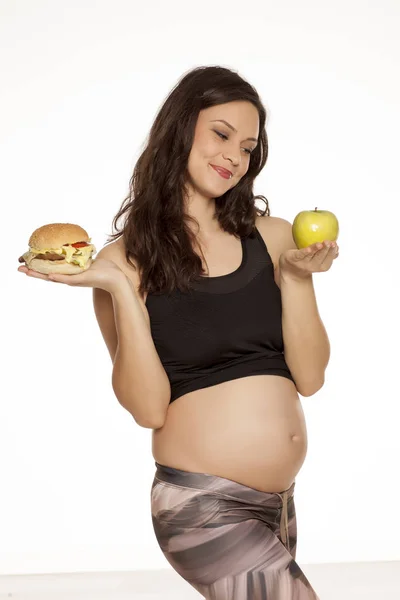 Hungry Pregnant Woman Choosing Apple Hamburger White Background — Stock Photo, Image