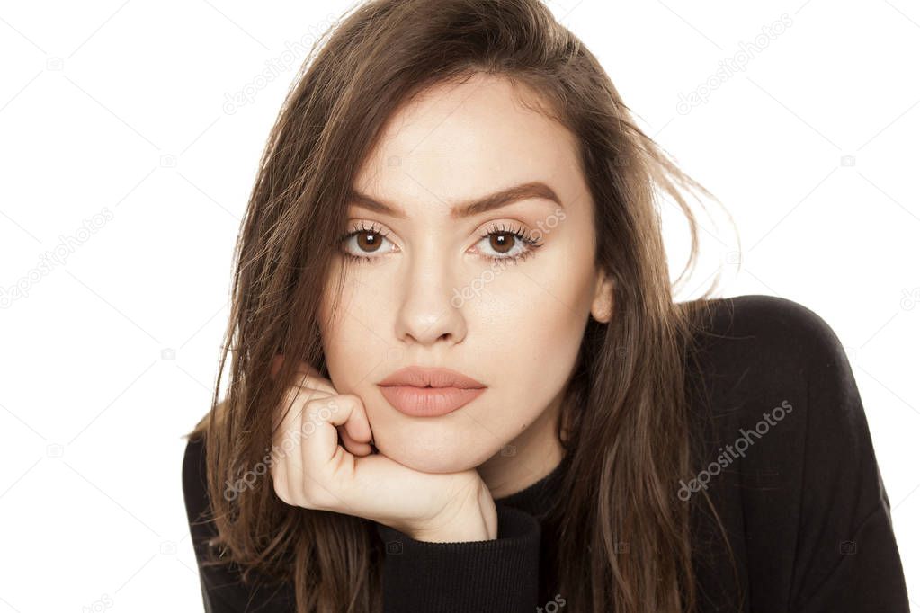 Portrait of a beautiful young woman leaning on her arm and looking at the camera on a white background