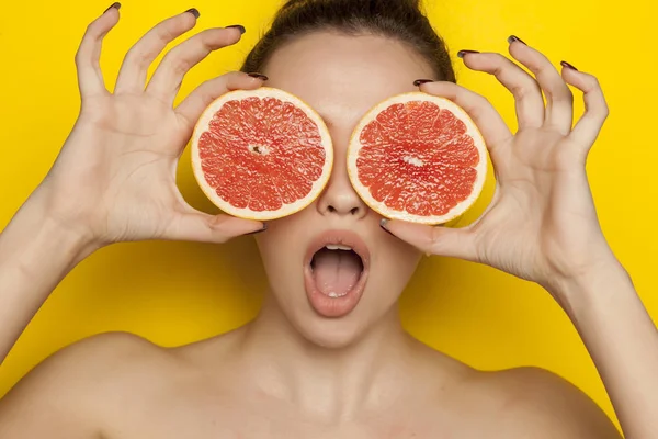 Surprised Young Woman Posing Slices Oranges Her Face Yellow Background — Stock Photo, Image