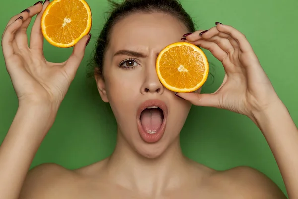Surprised Young Woman Posing Slices Oranges Her Face Green Background — Stock Photo, Image