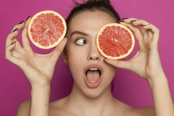 Jovem Mulher Surpreso Posando Com Fatias Toranja Vermelha Seu Rosto — Fotografia de Stock