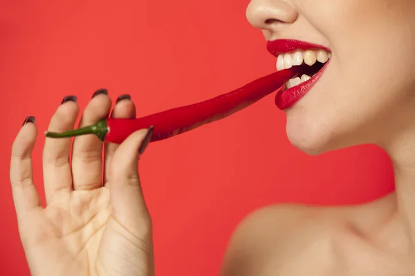 Jonge Sexy Vrouw Bijten Een Chili Peper Een Rode Achtergrond — Stockfoto