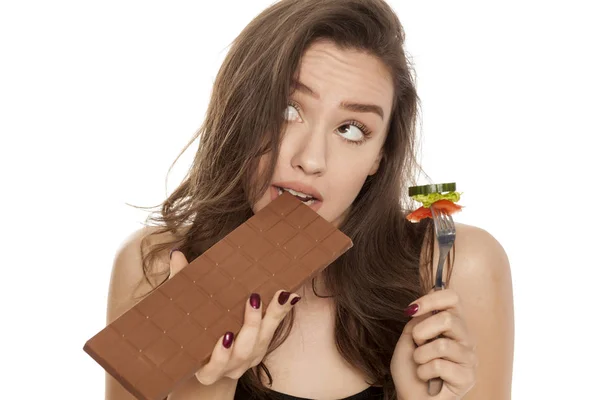 Mujer Joven Comiendo Chocolate Sosteniendo Tenedor Con Verduras Sobre Fondo —  Fotos de Stock