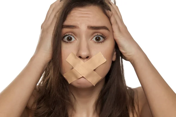 Jonge Vrouw Met Plakband Geschokt Haar Mond Een Witte Achtergrond — Stockfoto