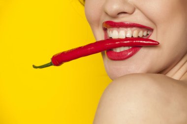 Biber dişleriyle sarı bir arka plan üzerinde tutan genç seksi kadın