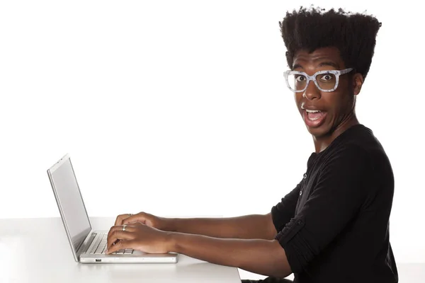 白い背景の上のノート パソコンをデスクで働いて笑顔と正の若いアフリカ系アメリカ人男 — ストック写真