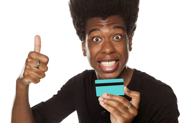 肯定的な幸せな若いアフリカ系アメリカ人男クレジット カードを保持していると 白い背景上に親指を表示 — ストック写真