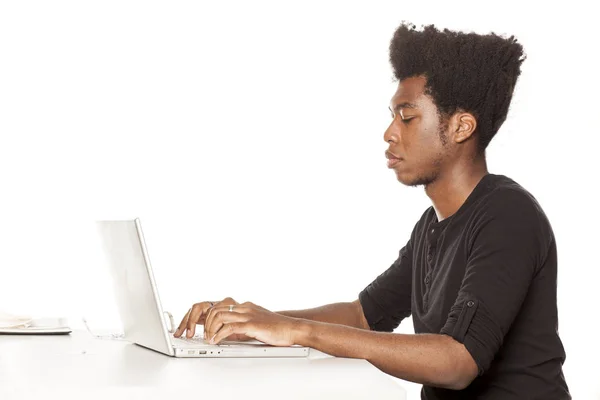 白い背景の上のラップトップをデスクで働いている若いアフリカ系アメリカ人の人 — ストック写真