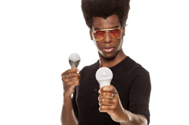 Beyaz bir arka plan üzerinde izole Led ampuller tutan genç Afro Amerikan yakışıklı olan. enerji kavramı kaydetme