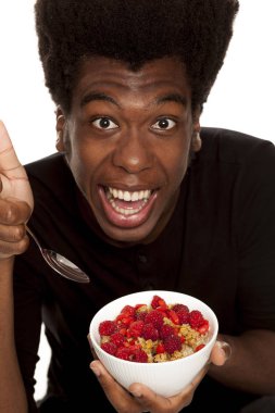 Beyaz bir arka plan üzerinde izole taze meyve ile tahıl yemek genç Afro Amerikan hipster yakışıklı olan. Sağlıklı gıda kavramı